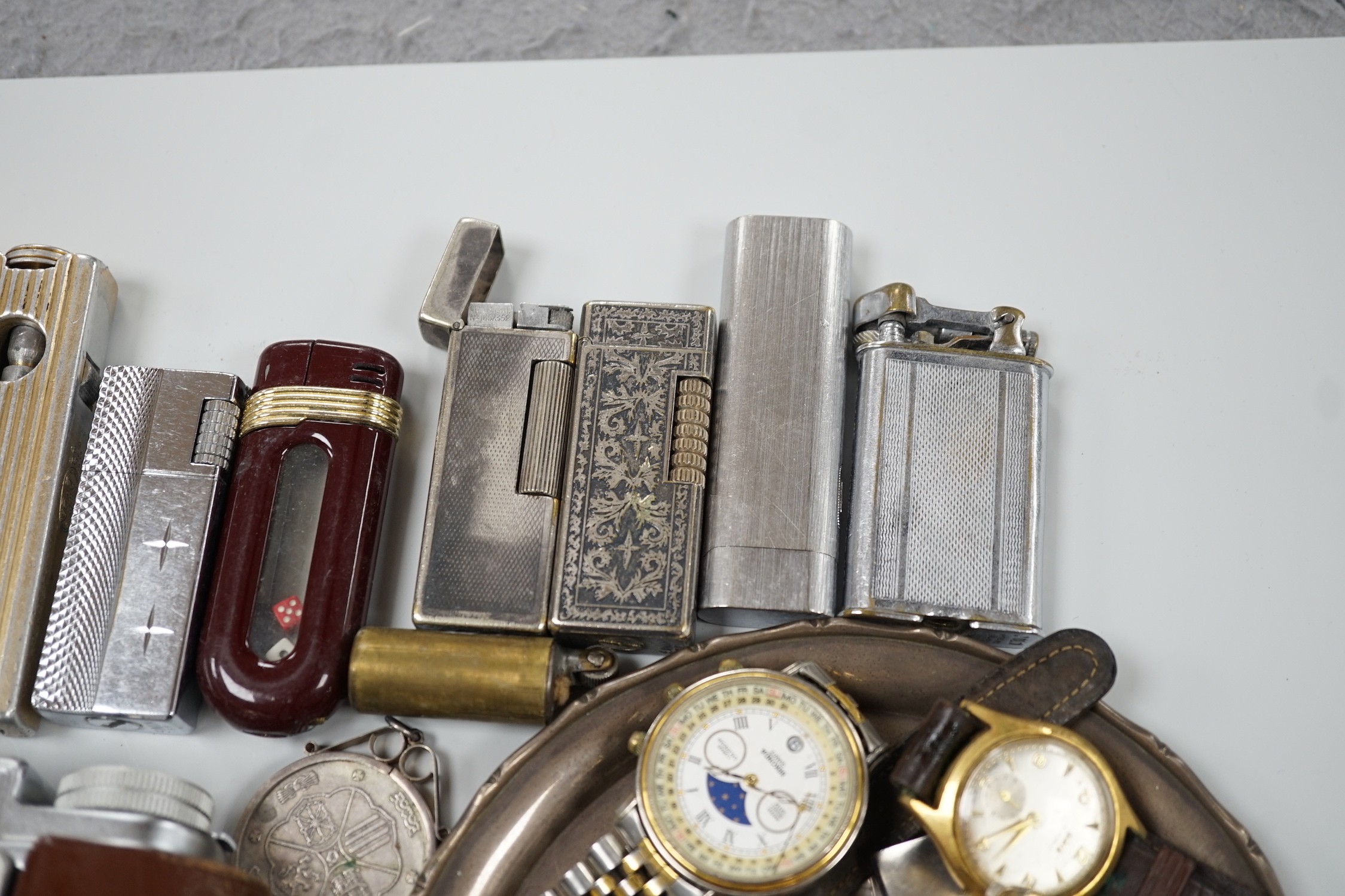 A collection of mixed wristwatches and cigarette lighters and a camera